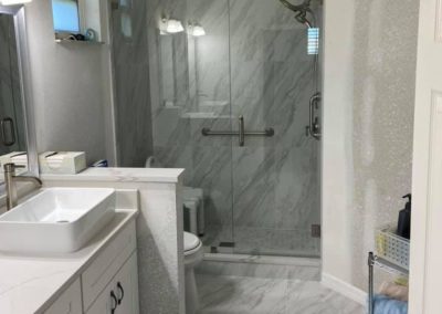 remodeled bathroom with white vessel sinks and glass shower